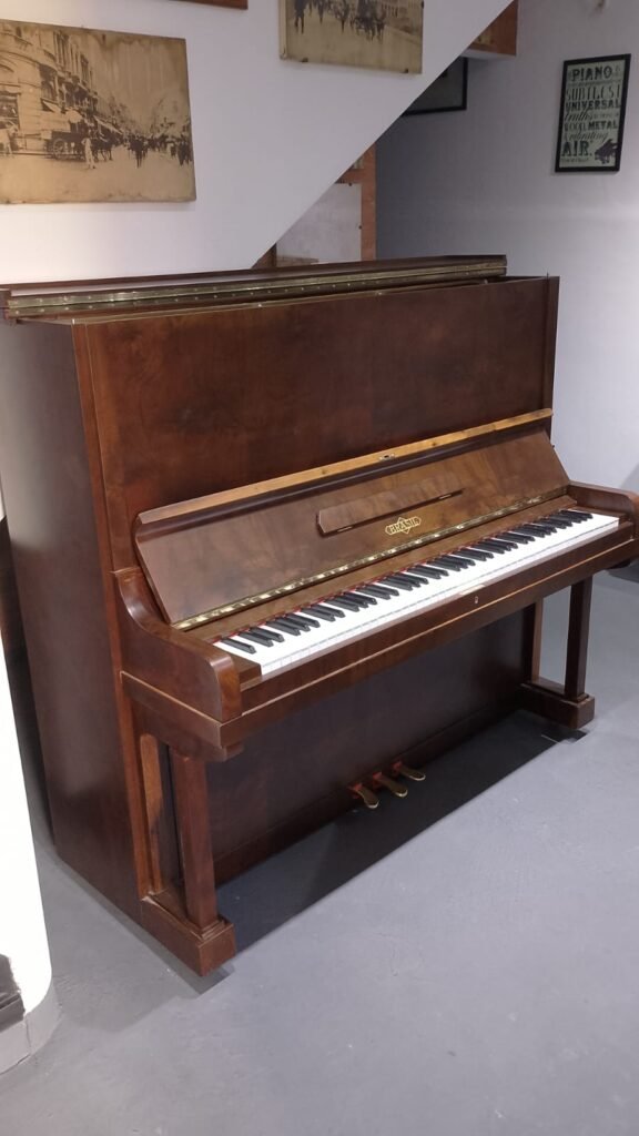 Piano acústico marrom, ideal para aluguel para estudo musical. Detalhe do piano vertical.