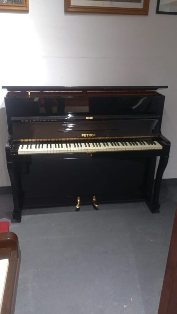 Piano vertical preto da marca Petrof para aluguel, ideal para estudo.