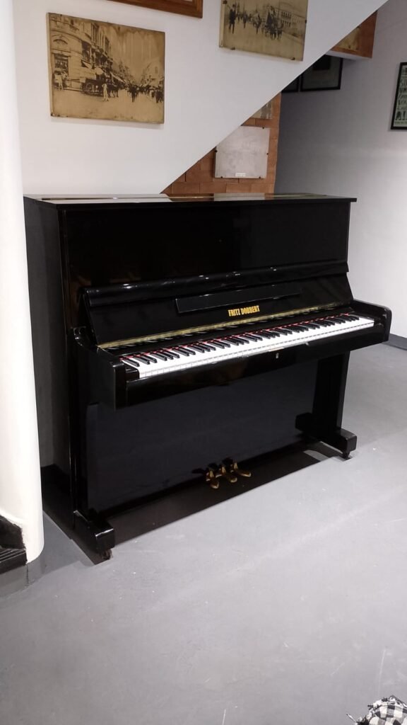 Piano acústico preto da marca Fritz Dobbert. Ideal para aluguel.