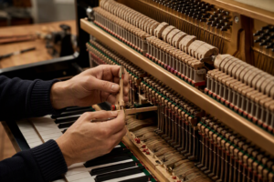 Técnico ajustando o mecanismo interno de um piano acústico